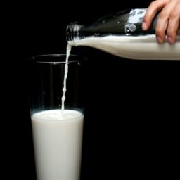 person pouring milk in highball glass