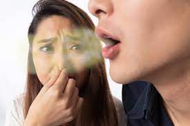 A person covering their nose with their hand, indicating bad breath or discomfort.
