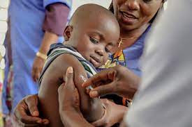 Immunization: Boy receiving vaccine on his arm from healthcare professional, smiling with mother