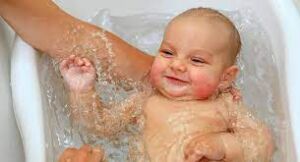A cheerful baby being bathed, smiling with joy and contentment.