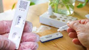 A close-up of a COVID-19 test kit, including a swab, test tube, and a positive/negative result indicator.
