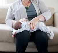 A parent holding a baby across their lap, gently patting their back to help with burping.