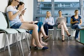 People sitting in the waiting area of the emergency room, using their electronic devices