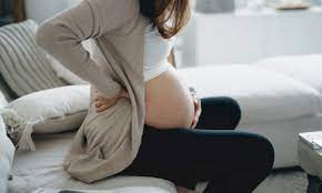 A close-up image of a pregnant belly, gently cradled by the person's hands. The skin is smooth and the focus is on the rounded shape of the abdomen, symbolizing pregnancy. The background is softly lit, creating a warm and serene atmosphere.