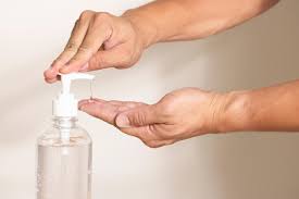 A person using hand sanitizer, with a small amount being dispensed onto their palm.