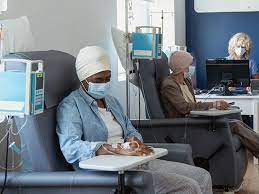 A patient seated in a hospital chair receiving chemotherapy through an IV in a calm, supportive environment.