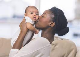 A woman gently kissing her baby, creating a bond of warmth and care.