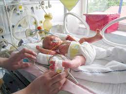 An image of a premature baby in an incubator, with delicate features and wrapped in soft, lightweight blankets. The baby is being carefully monitored with medical equipment, such as heart rate and oxygen monitors, in a neonatal intensive care unit (NICU) setting. The environment is calm and equipped with specialized care tools for premature infants