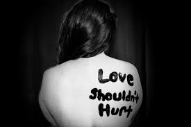 Silhouette of a person with 'Love shouldn't hurt' written on their back, depicting the emotional toll of domestic violence.