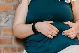 Person sitting and resting on a wall, reflecting on genetic factors influencing health, including obesity risk transmission.