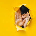 Person listening through a hole, emphasizing World Hearing Day awareness and the importance of hearing health.