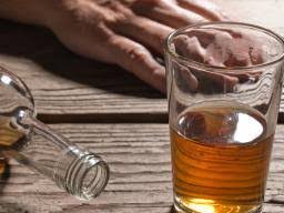 Glass of alcohol next to an empty bottle on the counter