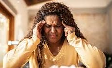 A person presenting with a severe headache, seen holding her head, may be experiencing intense discomfort and distress.