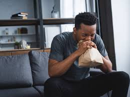 Man experiencing panic attack breathes into paper bag for relief