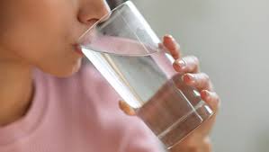 Person enjoying a refreshing glass of water for optimal health and well-being.