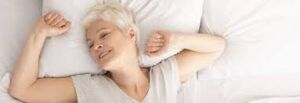 Image of a woman in bed, stretching and feeling rejuvenated after enjoying a night of quality rest. Achieve optimal well-being with good sleep habits.