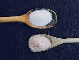 Spoonfuls of sugar and salt juxtaposed on a countertop, illustrating the dual impact on health and dietary choices.