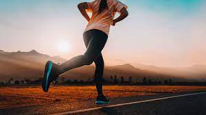 Woman enjoying exercise benefits by jogging on the road during the late afternoon.