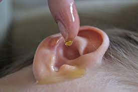 Person applying ear oil drop - Aiding ear health and hearing
