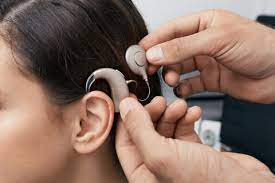 Person fitting hearing aid on child with hearing loss