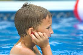 Boy in water holding his ear - Signs of Ear Discomfort