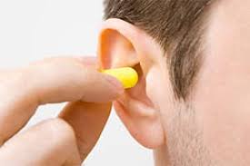 Person inserting yellow ear plug - Protecting against hearing loss