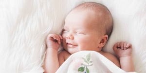 A close-up of a smiling baby with a joyful and content expression, showing a sense of satisfaction. The baby’s face is bright with satisfaction. The background is soft and neutral, emphasizing the baby's joyful expression. The image conveys warmth, innocence, and a sense of peace.
