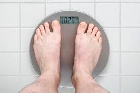 Person standing on a scale - Image depicting a person standing on a scale, representing the monitoring of weight loss progress