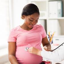 Screenings: Pregnant woman at antenatal clinic, doctor listening to baby's heartbeat with a stethoscope