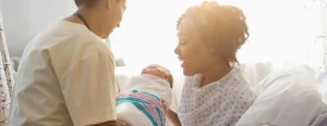 Healthcare professional handing a newborn baby to a mother