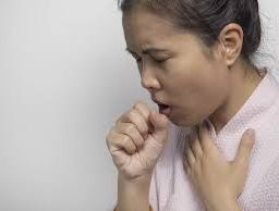 Woman coughing while holding her hand over her mouth due to the common cold
