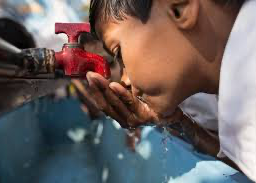Child drinking water directly from the pipe