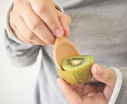 Person enjoying a kiwi with a spoon