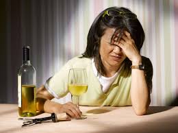 Woman with a headache next to a bottle and glass of wine