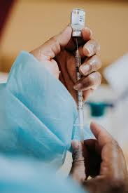 A healthcare professional preparing a dose of hepatitis B vaccine from a vial.