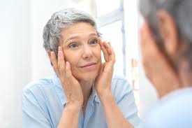 An aged woman assessing her face in the mirror, showcasing a moment of introspection and self-care.