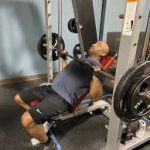 Man performing weightlifting exercises on exercise equipment, demonstrating proper form and technique for a safe and effective workout routine.