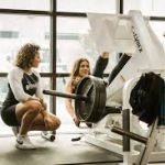 Exercise equipment image featuring woman at the gym receiving guidance from her trainer, emphasizing the importance of professional supervision in exercise routines for enhanced safety and effectiveness.