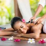 Woman treating herself to a hot stone massage therapy. Experience ultimate relaxation and mental refreshment through indulgent self-care.