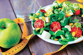 Health and nutrition concept: A crisp apple surrounded by a measuring tape, placed near a plate of assorted vegetables, symbolizing a balanced and wholesome diets.