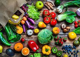 A variety of fruits and vegetables including cabbage, lettuce, orange, chives, and peppers scattered from a bag, emphasizing their impact on blood sugar levels.