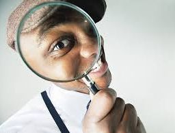 Man examining closely through a magnifying glass, emphasizing the importance of clear vision and attention to detail.