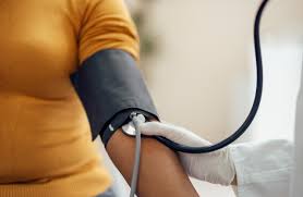 Image of a blood pressure monitor with a cuff, displaying readings on the digital screen. The monitor is typically used to measure a person's blood pressure, consisting of a cuff that inflates around the upper arm and a device that records systolic and diastolic pressure values