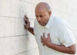 Man gripping his chest in distress indicative of a potential heart attack.