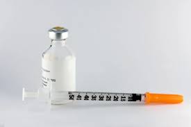 Vial of insulin medication with a syringe placed next to it, used for managing blood sugar levels in individuals with diabetes.