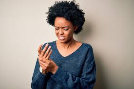 Woman holding right hand in discomfort due to neuropathy symptoms.