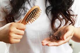 Close-up of a woman with a hairbrush and strands of hair in hand