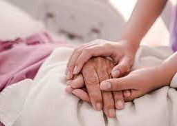 A caregiver provides gentle mobility assistance to a bedridden person, holding their hands with compassion. This scene illustrates the essential role of caregivers in promoting mobility and well-being for individuals confined to bed. The caregiver's support contributes to maintaining dignity and fostering a compassionate caregiving environment.