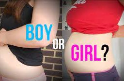 Two pregnant women side by side, one with a boy's sign, the other with a girl's sign, both showcasing their abdomens.