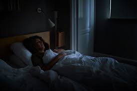 person laying in bed asleep peacefully in bed in a darkened room 
